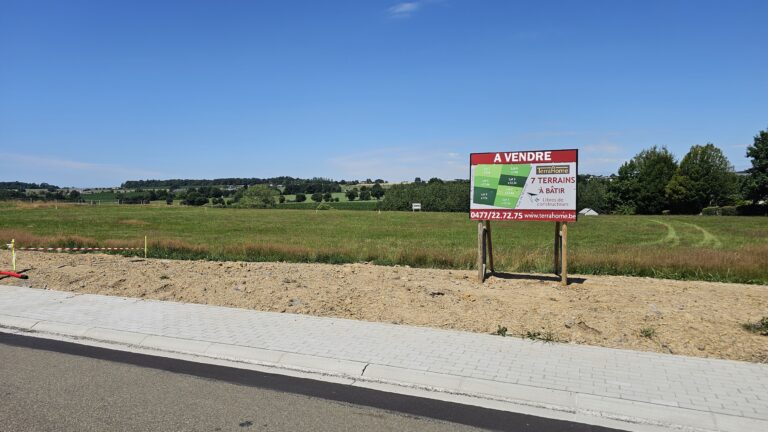 Un terrain en bord de route de 12 ares avec 4 façades présente un panneau 